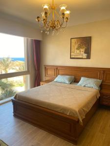 1 dormitorio con 1 cama grande y lámpara de araña en Il monte galala, en Ain Sokhna