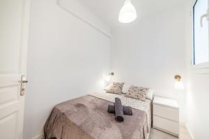 Un dormitorio blanco con una cama con dos zapatillas. en Carrer de Santa Madrona, 1 en Barcelona