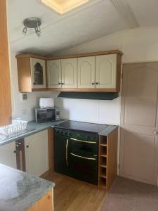 a kitchen with a black stove and a microwave at A7 caravan The Chase Ingoldmells in Ingoldmells