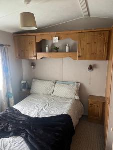 a bed in a small room with wooden cabinets at A7 caravan The Chase Ingoldmells in Ingoldmells