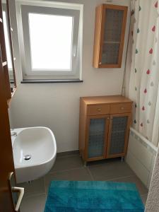 a bathroom with a white sink and a window at Ferienwohnung Emily in Friesenheim +6 photos