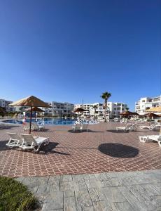eine Gruppe von Stühlen und Sonnenschirmen auf einer gemauerten Terrasse in der Unterkunft Magnific apartament en cabo negro in Tétouan