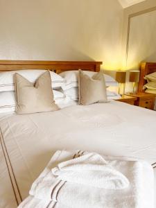 Cama blanca con sábanas y almohadas blancas en Knockview, en Aughrim