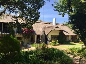 a cottage with a thatched roof with a garden at De Witt'e Guest House in Bloemfontein