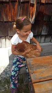 a little girl sitting on a bench holding a bird at Apartment Aineckblick in Sankt Michael im Lungau