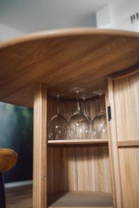a shelf with wine glasses in a wooden cabinet at Suite 13 im Wald mit Balkon in Amberg