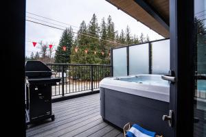 a hot tub on a deck with a grill at The Céilí Cottage by Revelstoke Vacations in Revelstoke