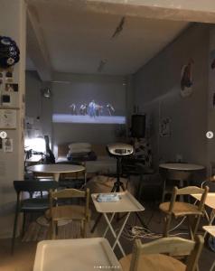 une salle avec des tables, des chaises et un écran de projection dans l'établissement Your Small Theater, à Séoul