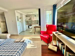 a living room with a bed and a red chair at SAWA 4 metro fast WiFi 1 Gbs 70TV Netflix HBO Disney in Warsaw