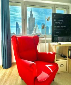 una sedia rossa seduta in una stanza con finestra di SAWA 4 metro fast WiFi 1 Gbs 70TV Netflix HBO Disney a Varsavia