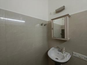 a white bathroom with a sink and a mirror at Calcutta Backpackers in Kolkata