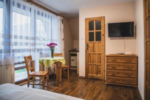 een slaapkamer met een tafel en een televisie en een tafel met stoelen bij Pokoje Gościnne na Stromej in Zakopane