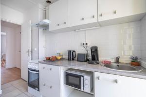 uma cozinha branca com um lavatório e um micro-ondas em Charming apartment in Marseille - Welkeys em Marselha