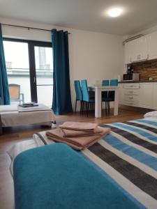 a room with two beds and a table with blue chairs at Studio Selena Vamaland in Vama Veche