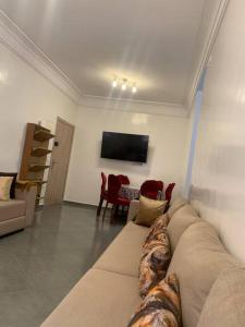 ein Wohnzimmer mit einem Sofa und einem TV in der Unterkunft Spacieux appartement 2 chambres 1 salon à 5 minute de l aéroport Marrakech Ménara in Marrakesch