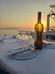 a bottle of wine sitting on a table with wine glasses at Paralia Ofriniou Sea view apartment in Orfánion