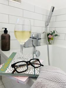 a glass of wine and a book on a table at Blossom Lodge - 3 Bedroom Bungalow in Norfolk Perfect for Families and Groups of Friends in Narborough