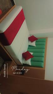 Una cama con almohadas rojas y verdes. en Hotel Sarovar Regenta, en Mathura