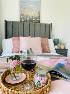ein Tablett mit einem Glas Wein und Blumen auf dem Bett in der Unterkunft Blossom Lodge - 3 Bedroom Bungalow in Norfolk Perfect for Families and Groups of Friends in Narborough