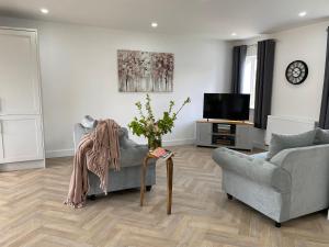a living room with a couch and a tv at Blossom Lodge - Detached bungalow near Kings Lynn in Narborough