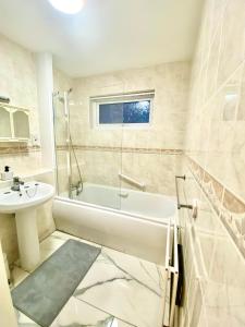 uma casa de banho com uma banheira e um lavatório em Luxury Large Four Bedroom Family Home Free Car Park em Luton