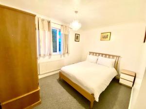 um quarto com uma cama branca e uma janela em Luxury Large Four Bedroom Family Home Free Car Park em Luton
