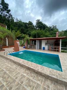 a swimming pool in front of a house at Fazenda São Lourenço na Serra da Mantiqueira in Queimada