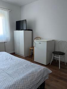 um quarto com armários brancos, uma cama e uma televisão em Györgyi Haus em Bük