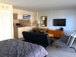 ein Schlafzimmer mit einem Bett, einem Stuhl und einem TV in der Unterkunft Ilikai Apt 1042 - Spacious Studio with Ocean-Lagoon Views in Honolulu