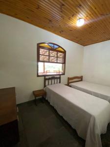 a room with two beds and a window in it at Fazenda São Lourenço na Serra da Mantiqueira in Queimada