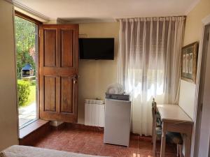 Habitación con nevera, escritorio y ventana. en alojamiento con jardin y barbacoa en Cangas de Onís