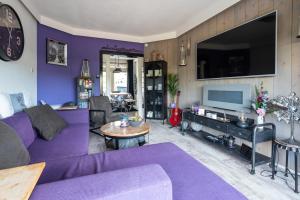 ein Wohnzimmer mit einem lila Sofa und einem TV in der Unterkunft Beautiful house n.Amsterdam, suitable for families in Hilversum