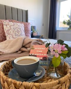 uma mesa com uma chávena de café e um livro em Blossom Lodge - 3 Bedroom Bungalow in Norfolk Perfect for Families and Groups of Friends em Narborough