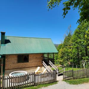 a wooden cabin with a fence and a hot tub at Koliba Pčelica 1 in Bijelo Polje