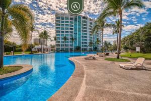 a resort swimming pool with palm trees and a building at Amazing 2BR Condo with Pool and Access to VIDANTA in Nuevo Vallarta 