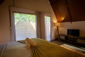 a bedroom with a bed with a window and a television at Cabana Gameleira - Viagem Inspirada in Fernando de Noronha
