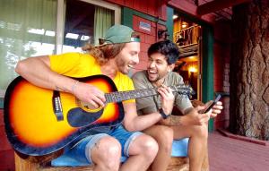 two men sitting on a bench playing a guitar at ITH Big Bear Lake Hostel & Retreat Center in Big Bear Lake