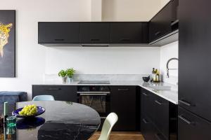 eine Küche mit schwarzen Schränken und einem Tisch mit einer Schale Obst in der Unterkunft Luxurious Couples Smart Home in Malmö