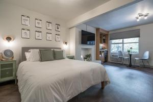 a bedroom with a large white bed and a living room at The Local Motel & Shops in Eugene