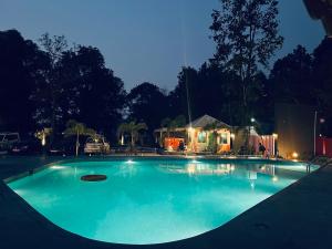KADAMBINI JUNGLE RESORT في لاتاغري: مسبح في الليل مع منزل في الخلفية