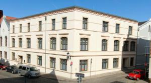 un gran edificio blanco con coches estacionados frente a él en Fründts Hotel en Wismar