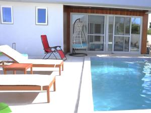 Long Bay HillsにあるOcean Pearl - A brand new one bedroom with pool, walkable distance to sunset beachのスイミングプールと赤い椅子付きの家