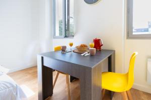 a dining room table with a yellow chair and drinks at Le Cosy Alfred Maury. Disneyland - Paris in Meaux