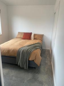 a bedroom with a bed with a red pillow at Hygge Eco Cabins in Jindabyne