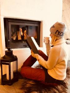 ヨーペランドにあるPreikestolen BaseCampの暖炉の前に座って本を読む女性