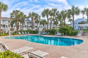 - une piscine avec des chaises et des palmiers dans un complexe dans l'établissement 62 Beach Club Villa, à Isle of Palms