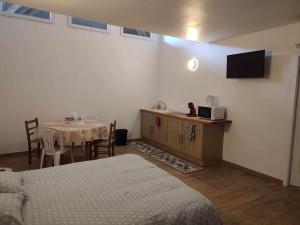 Zimmer mit einem Bett, einem Tisch und einem TV in der Unterkunft LE CHARME D OGNES in Ognes