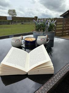 an open book sitting on top of a table with two cups at Bridie -rose Sleeps 4 to 6 with hot tub at extra cost in Kington