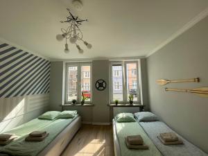 a bedroom with two beds and a chandelier and windows at Private rooms in the Old Town in Gdańsk