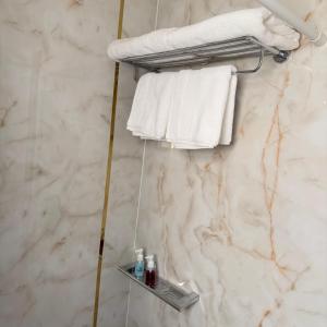 - un porte-serviettes dans la salle de bains pourvue de serviettes blanches dans l'établissement Elegance, à Firq